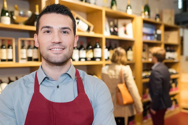 Vendedor sonriente hombre usando delantal en la tienda de vinos — Foto de Stock