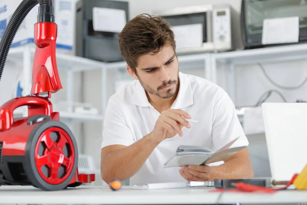 Reparador diagnosticando aspirador em sua oficina — Fotografia de Stock