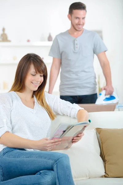 Happy woman sitting on couch reading magazine — Stock Photo, Image