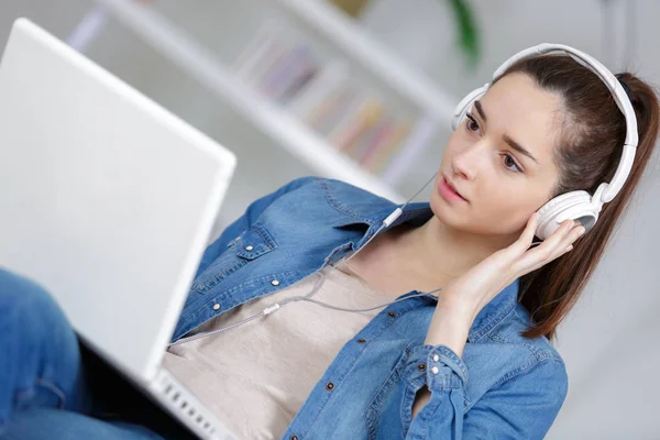 Jonge vrouw met hoofdtelefoon en laptop — Stockfoto