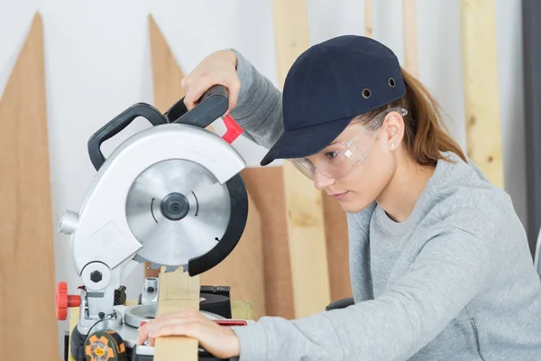 Женщина-плотник использует циркулярную пилу — стоковое фото