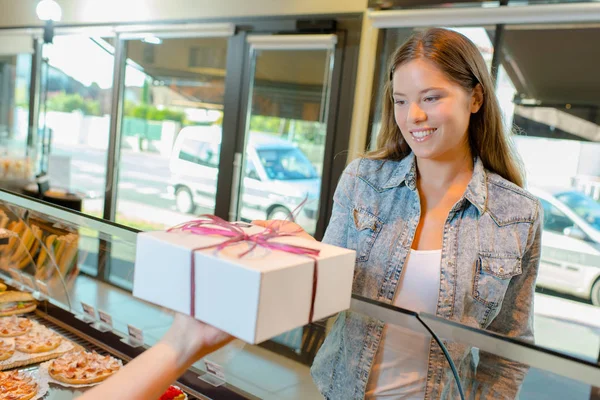 Dame nimmt Geschenkverpackung in Bäckerei an — Stockfoto