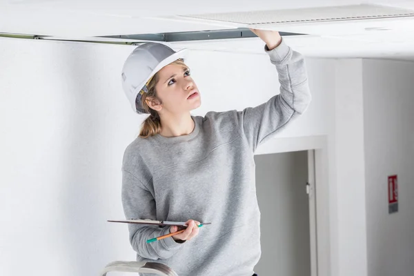 Mujer inspeccionando sobre techo suspendido —  Fotos de Stock