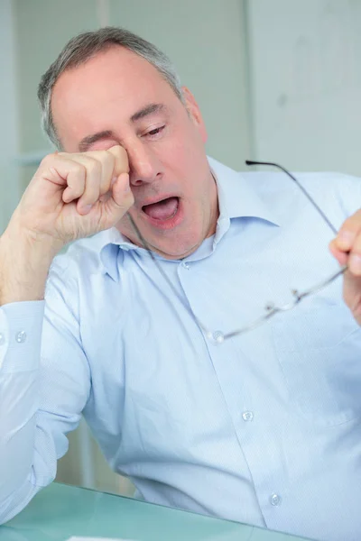 Mature businessman yawning in the office — Stock Photo, Image
