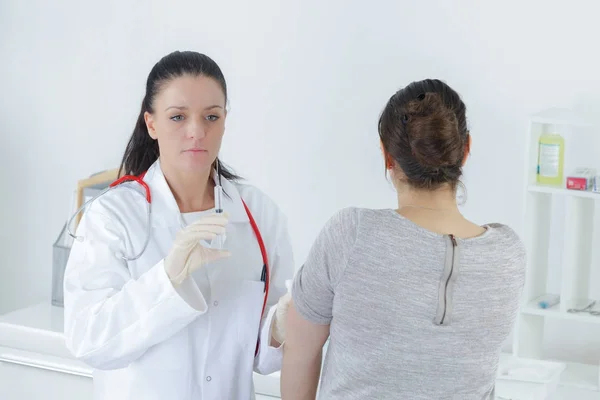 Doctora joven que se inyecta en el brazo — Foto de Stock