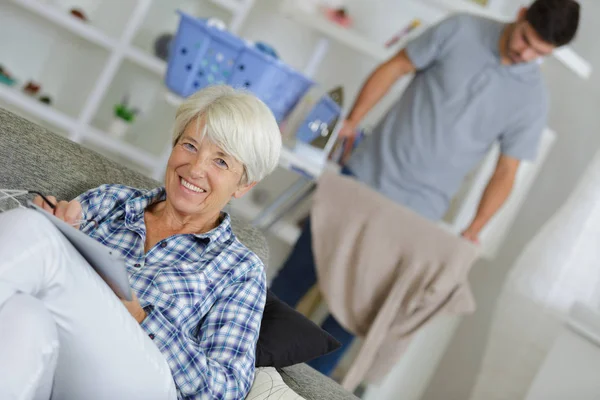 Cuidador masculino engomar lavanderia de agradável mulher idosa — Fotografia de Stock