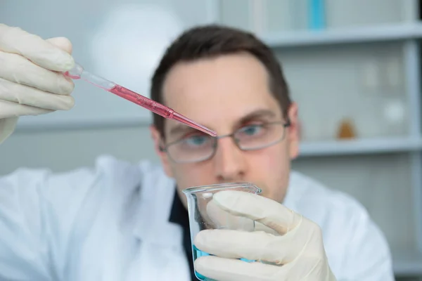 Científico añadiendo gota de líquido de la pipeta — Foto de Stock