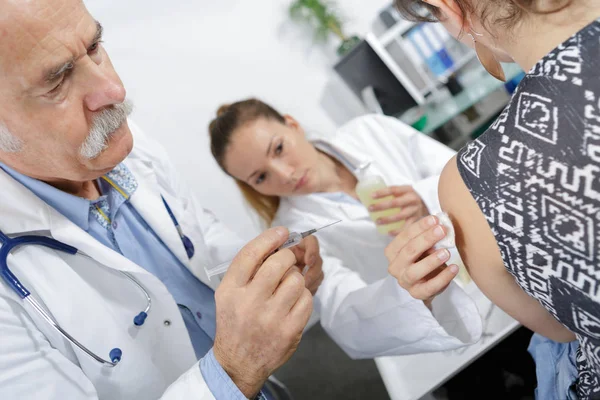 Senior doctor injecting patient with syringe — Stock Photo, Image