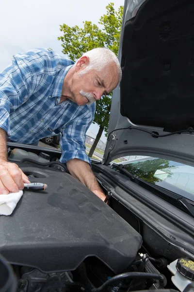 Oudere man reiniging van de motor van de auto met microfiber — Stockfoto