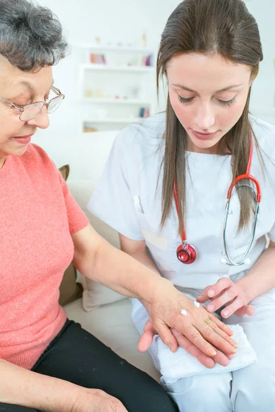 Sjuksköterska inspektera den äldre kvinnans sår — Stockfoto