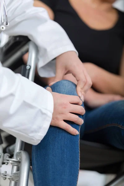 Male orthopedic doctor examining womans knee in clinic — Stock Photo, Image