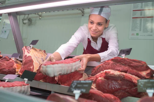 Carnicero hembra con manteca de cerdo y carne en mostrador de tienda — Foto de Stock