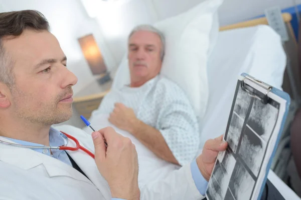 Doutor conversando com paciente do sexo masculino sênior na cama do hospital — Fotografia de Stock