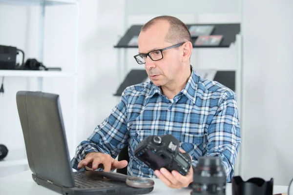 Técnico que examina e repara a câmera dslr — Fotografia de Stock