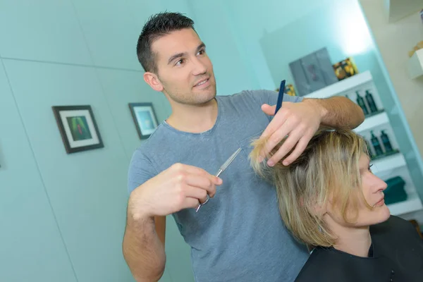 Cabeleireiro masculino está fazendo um corte de cabelo para uma mulher — Fotografia de Stock