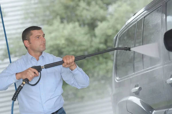 Hombre guapo está limpiando coche al aire libre — Foto de Stock