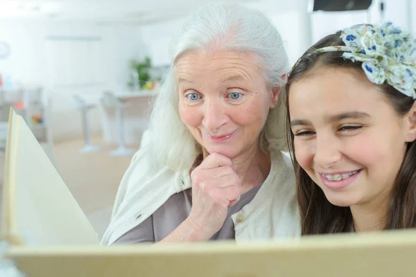 Oma haar kleindochter thuis lezen — Stockfoto