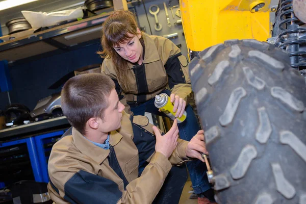 Aerosolové předávání žena k muži, kteří pracují na pneumatiky — Stock fotografie