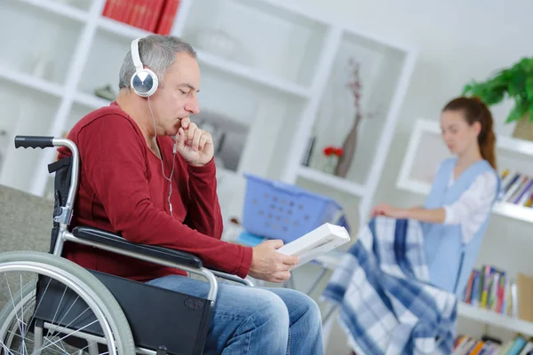Старший человек в инвалидной коляске с помощью санитара — стоковое фото