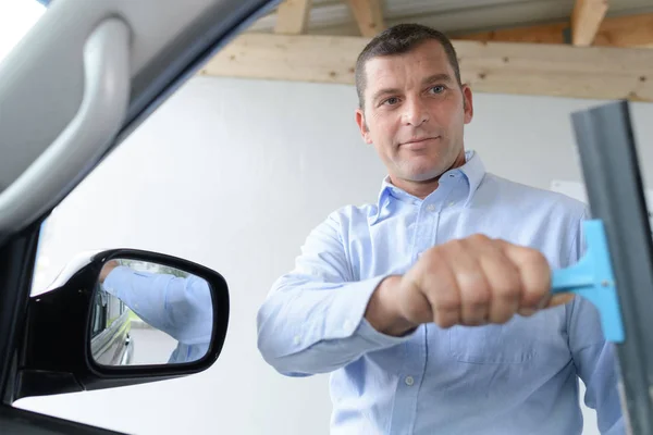 Hombre limpieza coche ventana con escobilla — Foto de Stock