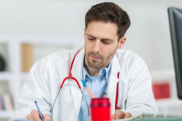 Medico che scrive prescrizione nel suo ufficio — Foto Stock