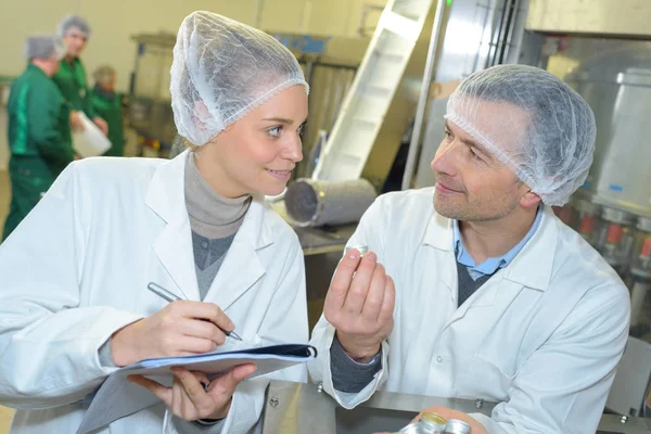 Científico hablando con su colega sujetando portapapeles en la fábrica — Foto de Stock