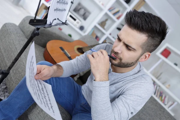 Jovem com livro para compor música com guitarra — Fotografia de Stock