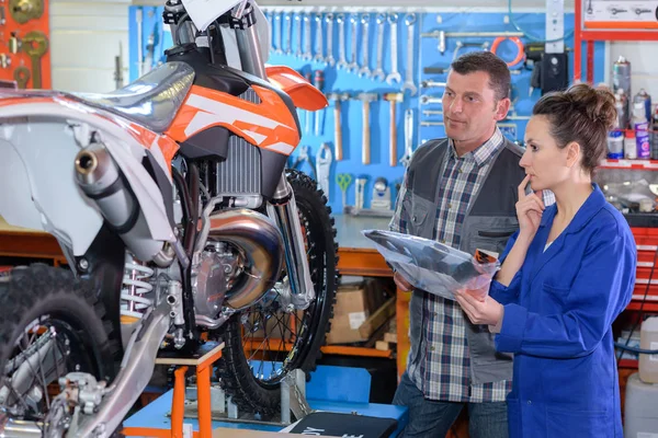 Trabajadora vendiendo una moto nueva en taller — Foto de Stock