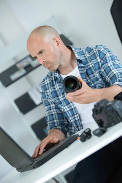 Man looking at broken photographic lense — Stock Photo, Image