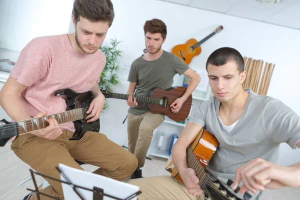 Счастливые молодые люди играют на гитаре с друзьями дома — стоковое фото