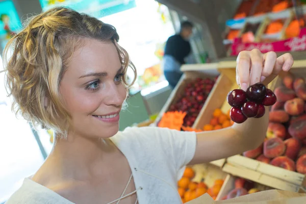 Jovem mulher compra cerejas um mercado semanal — Fotografia de Stock