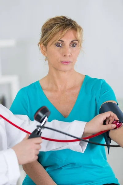 Dokter houdend van bloeddruk met rijpe vrouw — Stockfoto