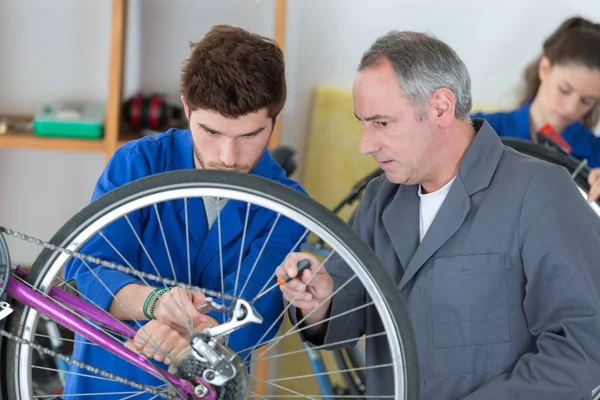 Homem que trabalha na oficina de bicicleta fixação de raios de bicicleta — Fotografia de Stock