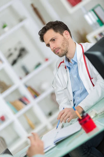 Schöner junger Arzt bei der Arbeit in seinem Büro — Stockfoto