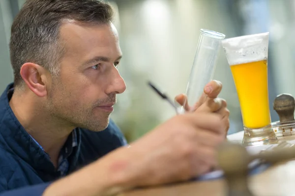 Hombre mirando cerveza artesanal oscura — Foto de Stock