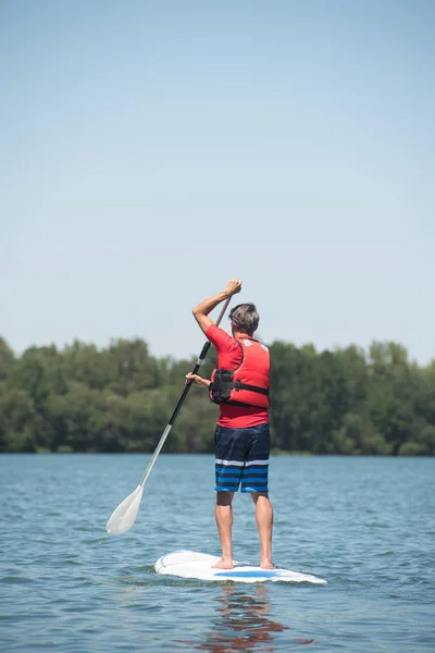 Uomo godendo di un giro sul lago con paddleboard — Foto Stock