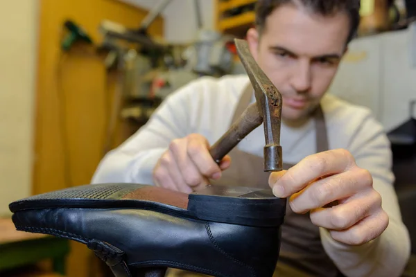Zapatero martillando un zapato en el taller — Foto de Stock