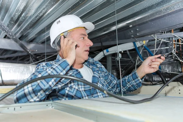 Trabajador haciendo montaje para un cable eléctrico en el techo — Foto de Stock
