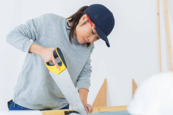 Carpintero femenino joven concentrado cortando madera — Foto de Stock