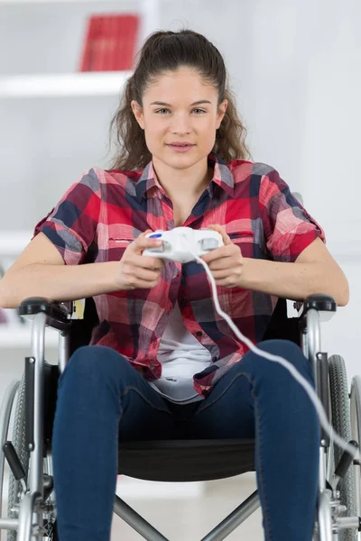 Mädchen im Rollstuhl spielt zu Hause Videospiele — Stockfoto