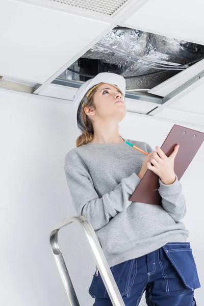 Bauunternehmer mit Klemmbrett schaut in Dachraum — Stockfoto