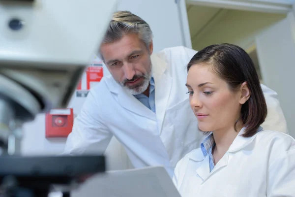 Hombre y mujer mirando el papeleo en el laboratorio — Foto de Stock