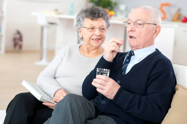 Ill senior couple talking a pill — Stock Photo, Image