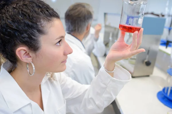 Fiatal laboratóriumi diák gazdaság egy lombik vörös folyadék — Stock Fotó