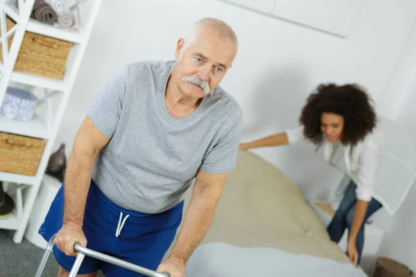 Senior homme avec marcheur à la maison avec femme d'aide à domicile — Photo