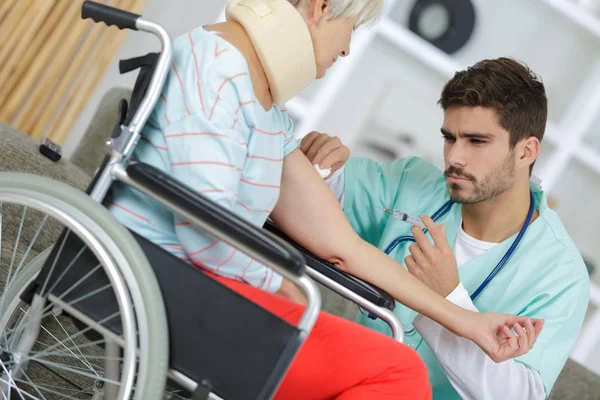 Sjukhusläkare som ger en äldre kvinnlig patient en injektion — Stockfoto