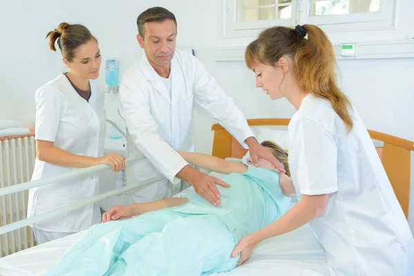 Медична команда вивчає пацієнта в лікарні — стокове фото