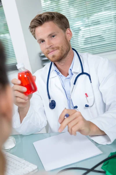 Doktor zobrazující láhev medicíny pacientovi — Stock fotografie