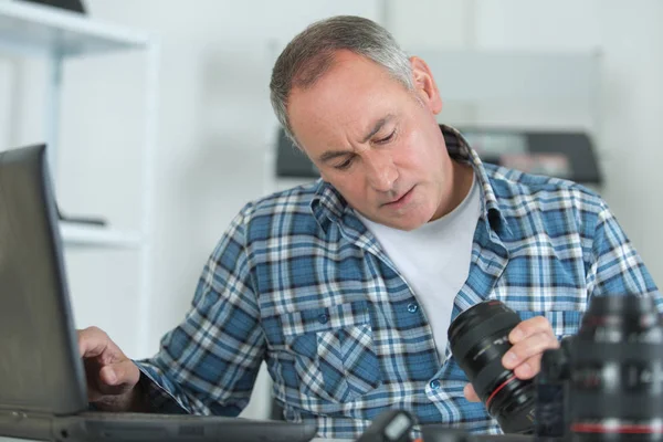 Muž čištění objektivu jeho digitální fotoaparát s speciální štětec — Stock fotografie