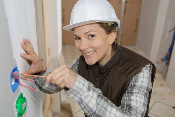 Glückliche Bauarbeiterin mit Schraubenzieher zur Befestigung der Steckdose im Haus — Stockfoto